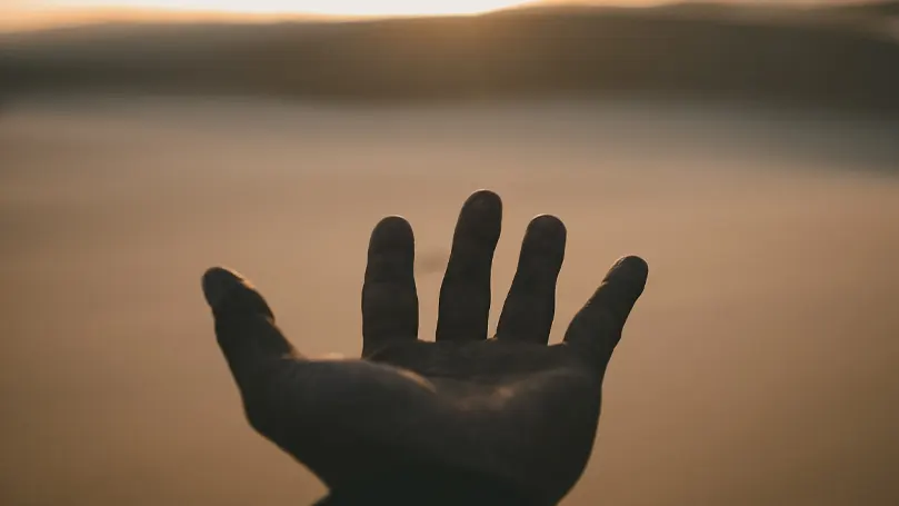 Een afbeelding van iemands hand met de palm naar de hemel gericht