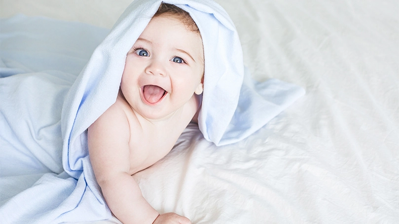 Een afbeelding van een baby met een handdoek van het hoofd