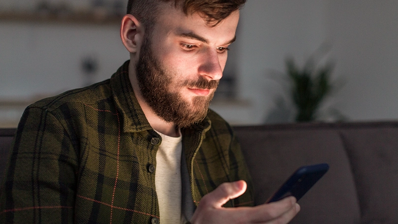 Een afbeelding van een man die naar zijn telefoon kijkt voordat hij naar bed gaat