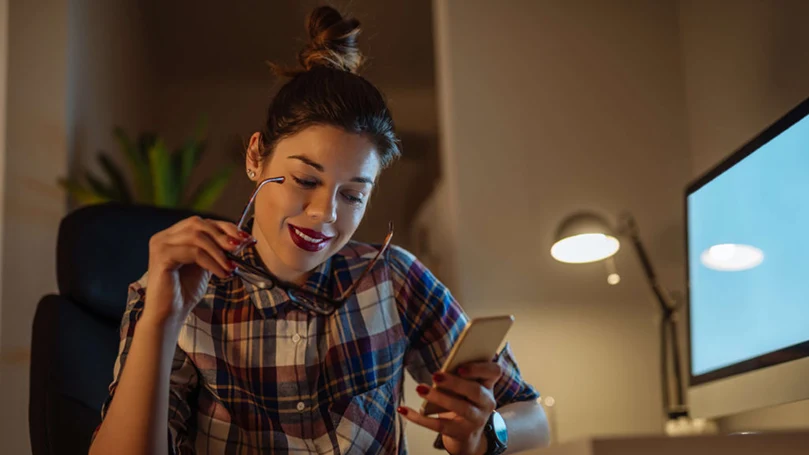 een afbeelding van een vrouw die haar telefoon voor een computer houdt