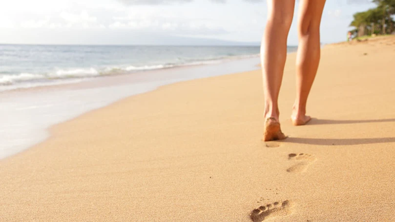 een vrouw loopt op het strand