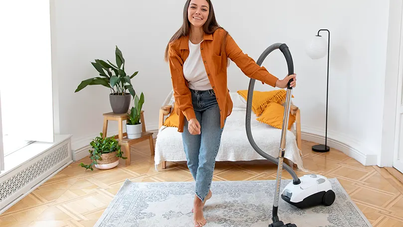 Een afbeelding van een vrouw die haar kamer stofzuigt