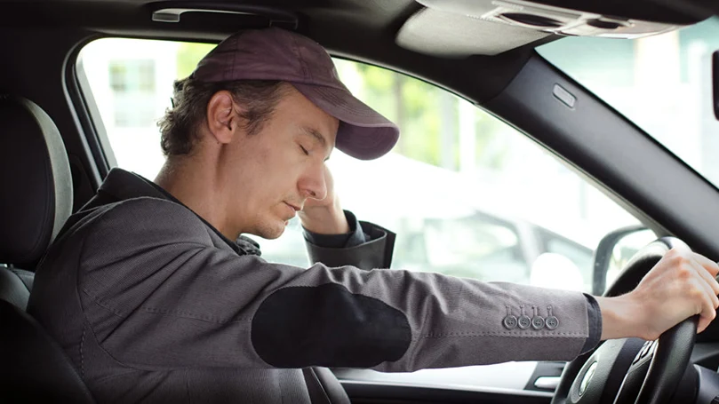 een afbeelding van een man die in zijn auto slaapt