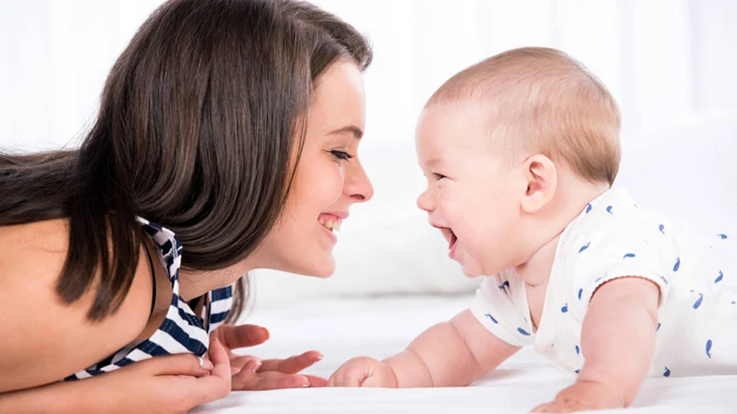 een afbeelding van een moeder die met een baby speelt