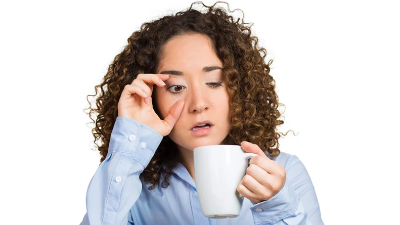 een afbeelding van een vrouw die suf wakker wordt en een kop koffie drinkt