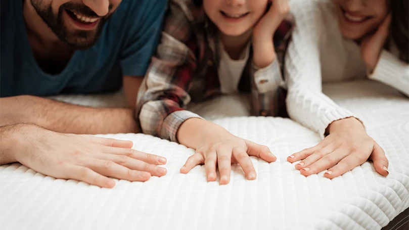 een gelukkig gezin liggend op een matras