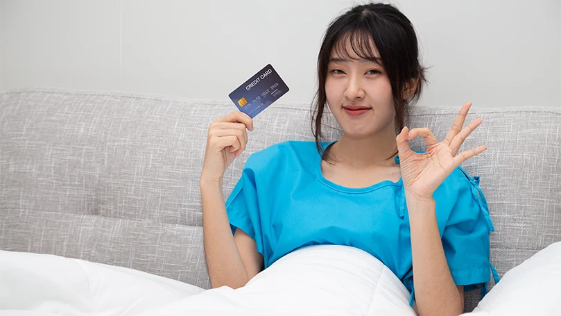 Een Aziatische vrouw in bed met haar creditcard