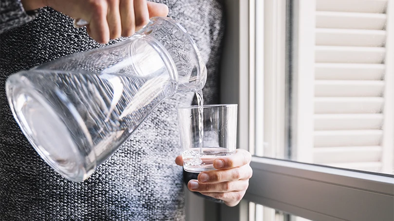 een afbeelding van een vrouw die zichzelf een glas water inschenkt