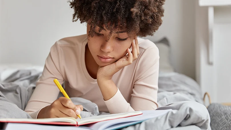 Een afbeelding van een vrouw die haar dromen opschrijft in een droomdagboek