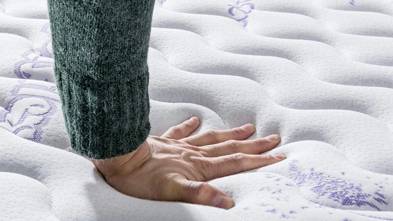 een afbeelding van een hand die op de toplaag van de Vesgantti Lavendel matras drukt