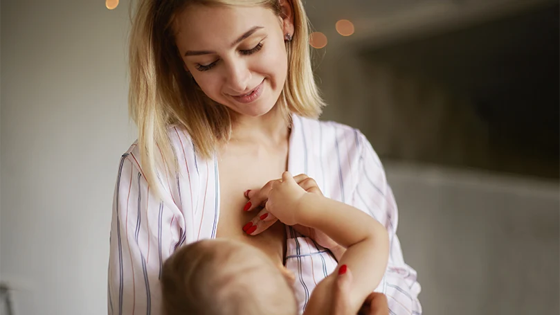 Een afbeelding van een moeder die haar baby borstvoeding geeft.