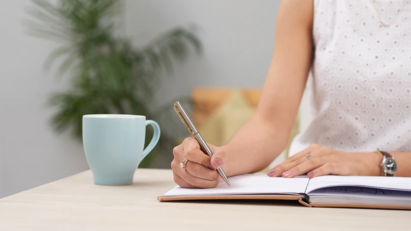 Een afbeelding van een vrouw die in haar dagboek schrijft.