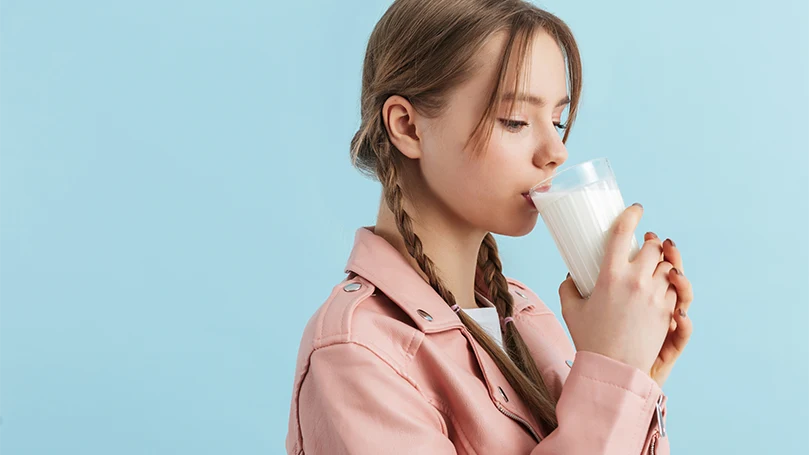 Een afbeelding van een jonge vrouw die een glas melk drinkt.