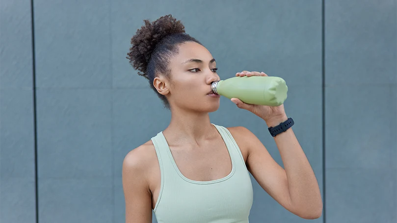 Een afbeelding van een jonge vrouw die water drinkt tijdens de training.