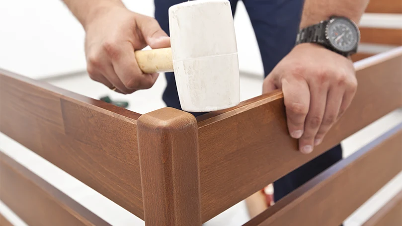 Een afbeelding van een man die een boxspring in elkaar zet en controleert of hij piept.