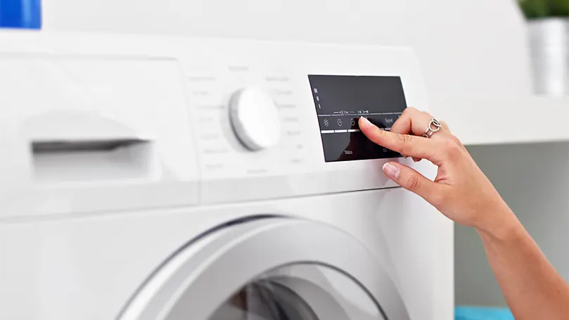 Een afbeelding van een vrouw die de lage droogstand van de wasmachine instelt.