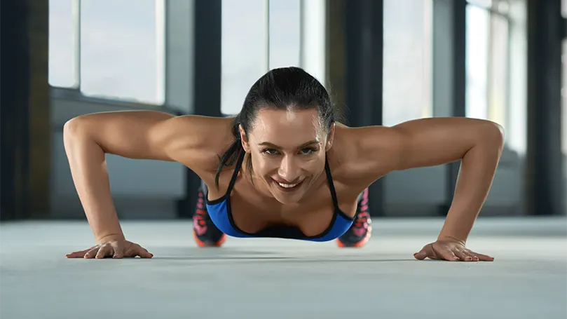 Een afbeelding van een jonge vrouw die een pushup doet.