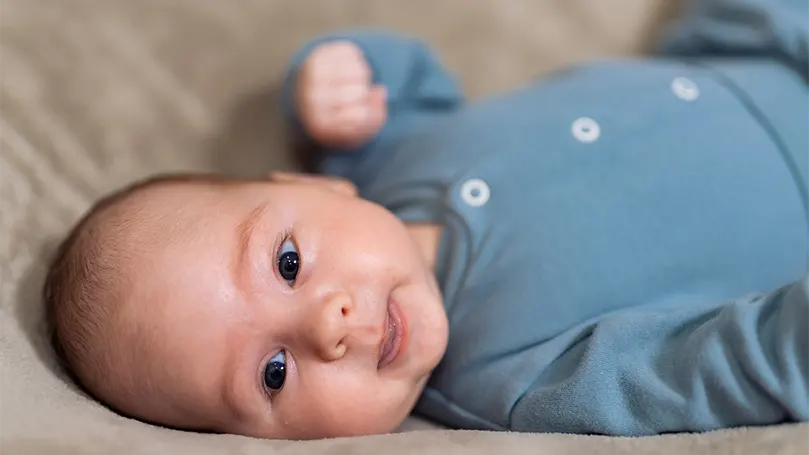 Een afbeelding van een 2 maanden oude baby die op zijn rug ligt.