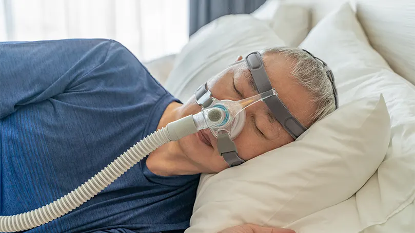 Een oudere man slaapt met CPAP-masker