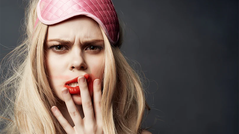 Een vrouw die lijdt aan slaapdronkenheid en een slaapmasker draagt.