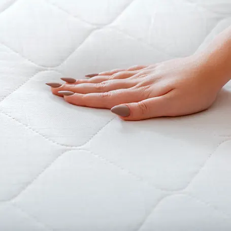 Een hand die op een matras drukt