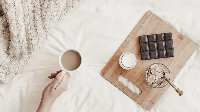 Een hand met een kop warme chocolademelk.