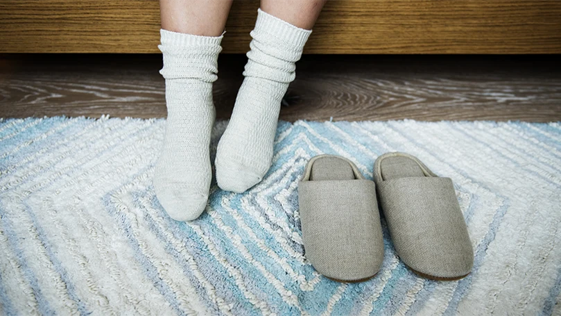 Een afbeelding van een persoon die wakker wordt en op een slaapkamerkleed staat.