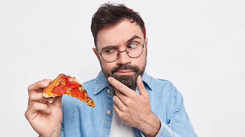 een-man-met-de-baard-houdt-een-pizzasnede vast