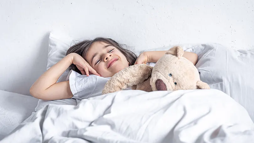 een-meisje-sliep-met-een-teddybeer-in-bed