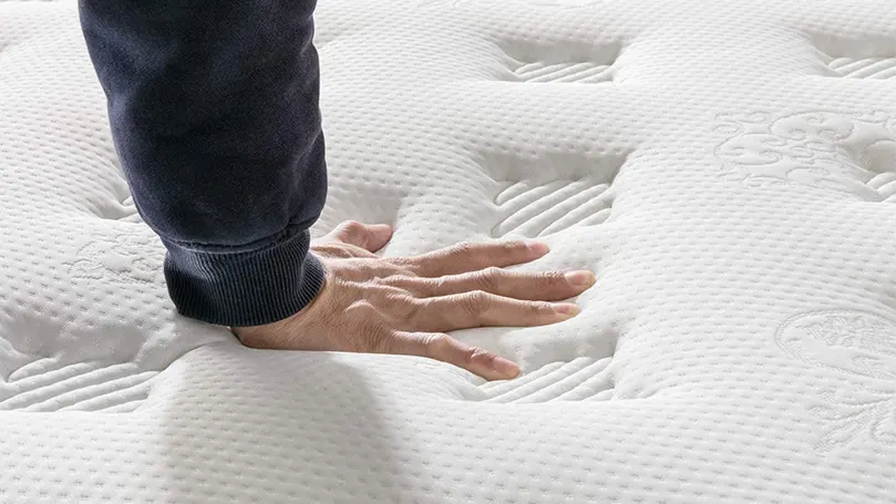 Een afbeelding van een man die met zijn hand op een pluche matras drukt.