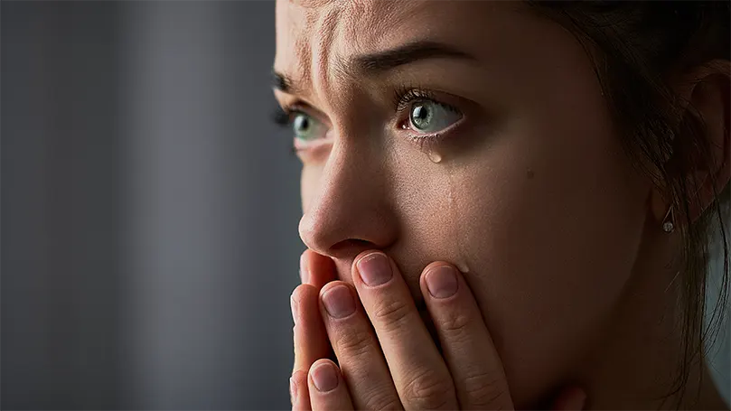 Een afbeelding van een verdrietige vrouw met groene ogen die huilt.