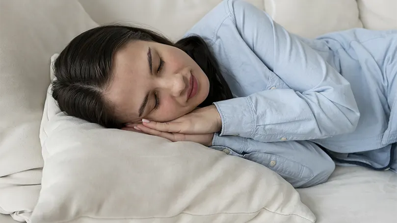 Een afbeelding van een vrouw die slaapt op een bank met beperkte ruimte.