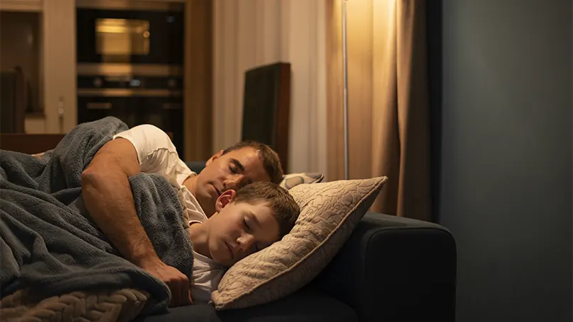 Een beeld van een vader & zoon slapend op een bank