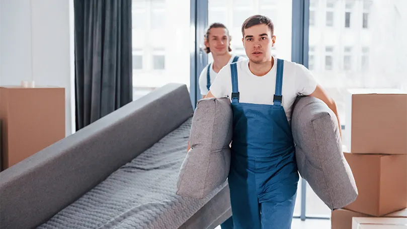 Een afbeelding van twee mannen van een professioneel bedrijf die een bed dragen.