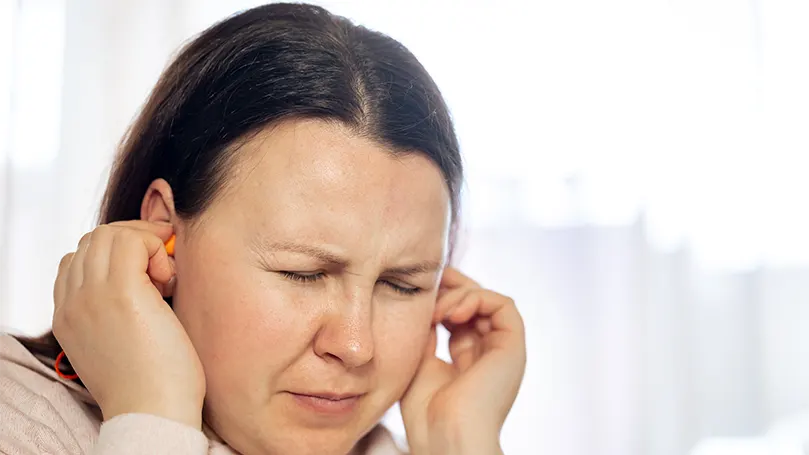 Een vrouw houdt haar oren vast vanwege problemen met een gescheurd trommelvlies.