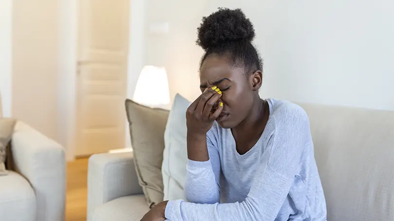 Een afbeelding van een jonge zwarte vrouw met een oogvermoeidheid,