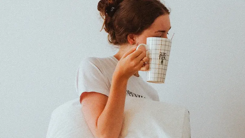 Een afbeelding van een vrouw die ontwaakt uit haar slaap en thee drinkt als onderdeel van haar ochtendroutine