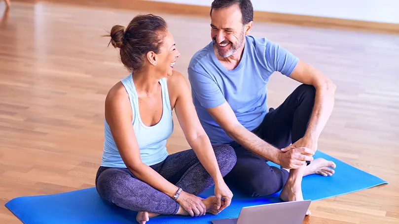 Een afbeelding van twee mensen die uitrusten op een yogamat na het sporten en actief bezig zijn