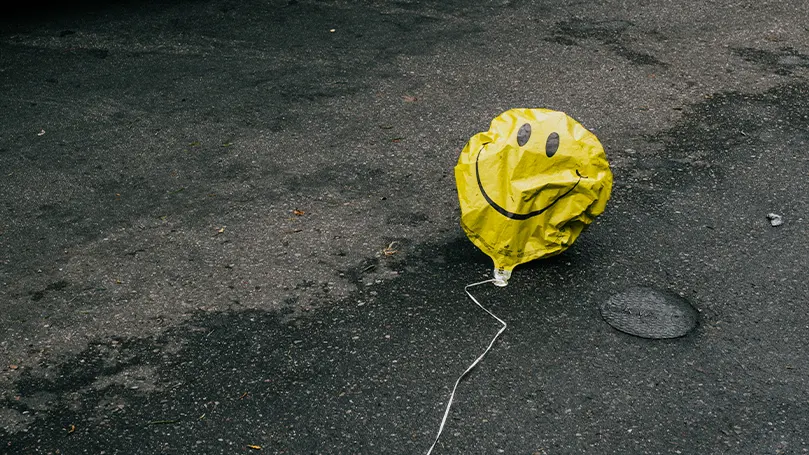 Een afbeelding van een leeggelopen ballon met een smiley erop