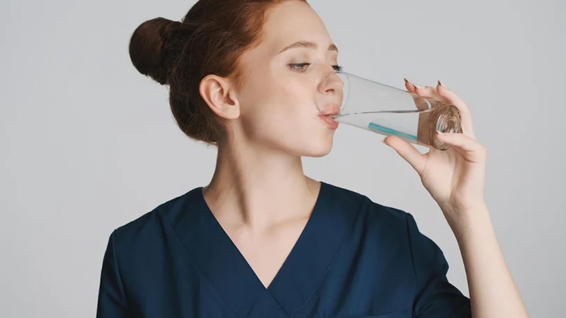 Een vrouw drinkt water - een van de beste huismiddeltjes tegen een kater.