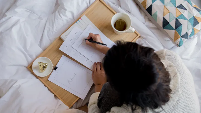 Een afbeelding van een vrouw die een dienblad in bed gebruikt.