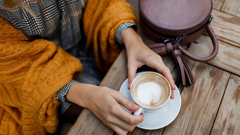 Een afbeelding van een persoon die buiten koffie drinkt