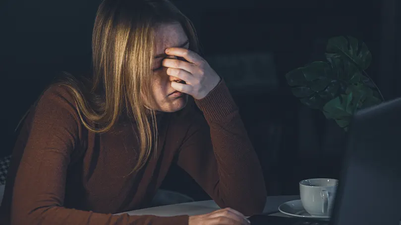 Een afbeelding van een vrouw met angst die 's nachts haar gezicht vasthoudt met haar hand