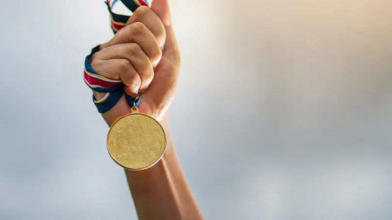 Een afbeelding van een hand met een gouden medaille