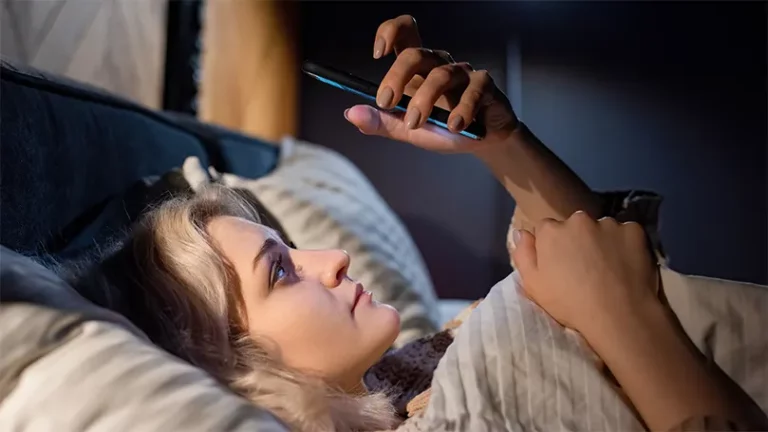 Een afbeelding van een vrouw in bed die een telefoon vasthoudt