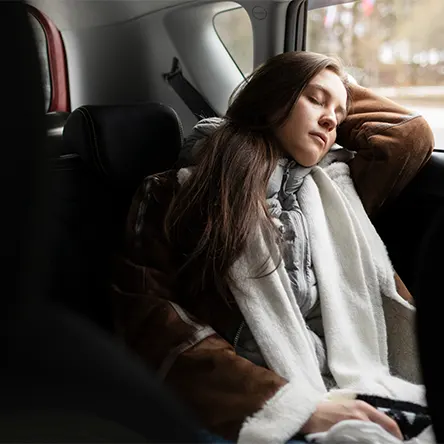 Een afbeelding van een vrouw die in haar auto slaapt.