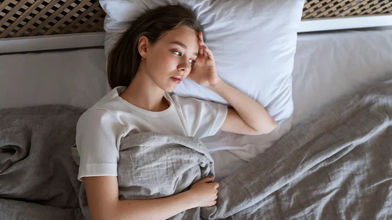 Een vrouw die in bed ligt terwijl ze het warm heeft