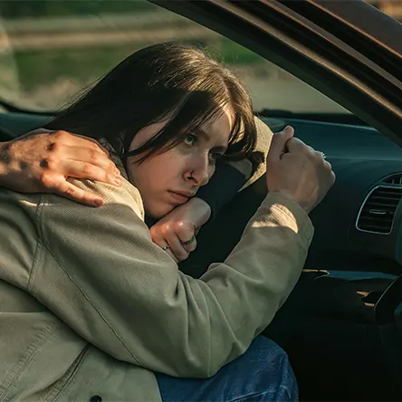 Een afbeelding van een vrouw die in haar auto slaapt.