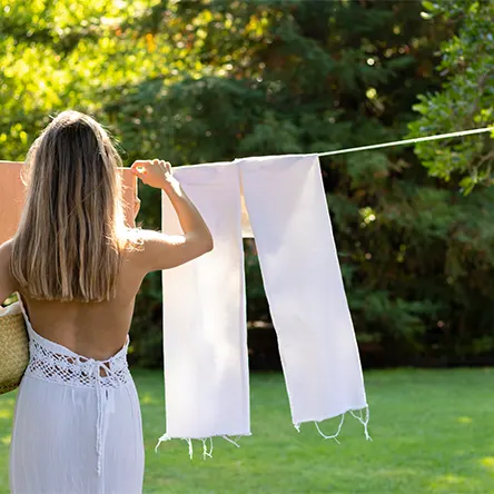 Een vrouw hangt wasgoed buiten te drogen