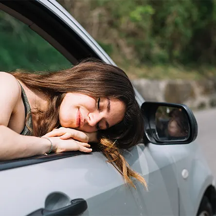 Een afbeelding van een vrouw die in haar auto slaapt.